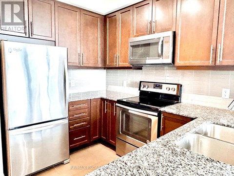 A kitchen with a stainless steel refrigerator, a microwave, and a stove top oven.