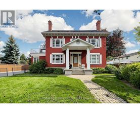 A red house with a white porch and a brick walkway leading to the front door.