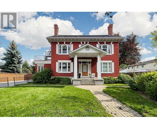 A red house with a white porch and a brick walkway leading to the front door.