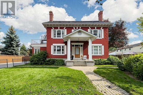 A red house with a white porch and a brick walkway leading to the front door.