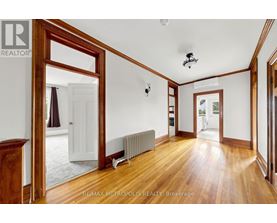 A room with wooden floors and white walls, with a large mirror on the left side.