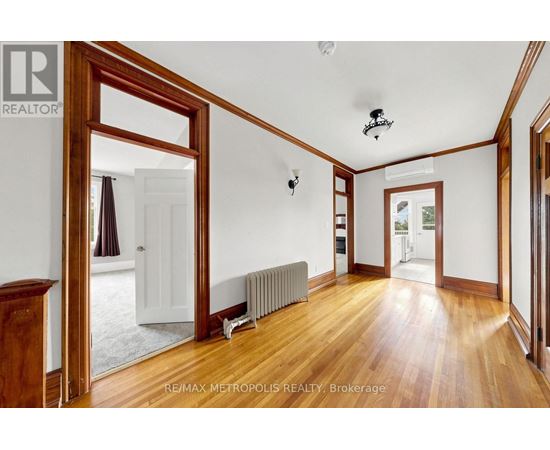 A room with wooden floors and white walls, with a large mirror on the left side.