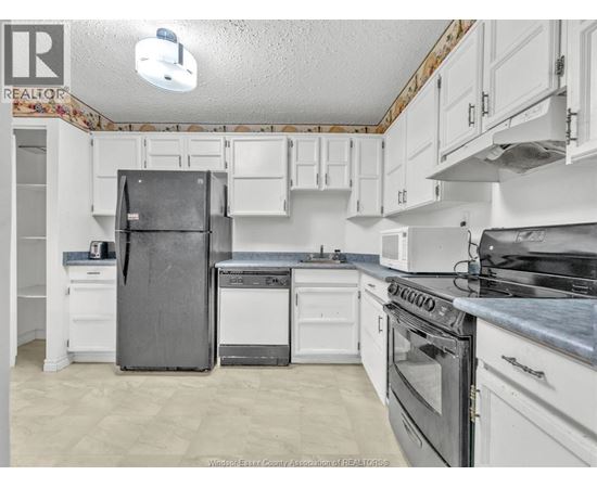 A kitchen with white cabinets and appliances.