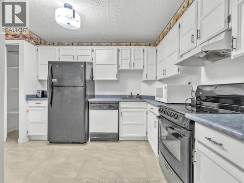A kitchen with white cabinets and appliances.