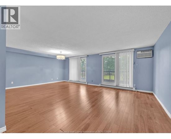 A spacious room with wooden flooring and blue walls.