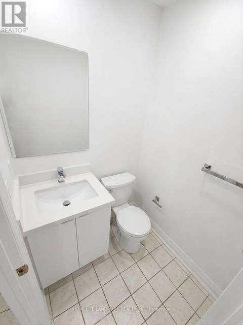 A white bathroom with a toilet, sink and mirror.
