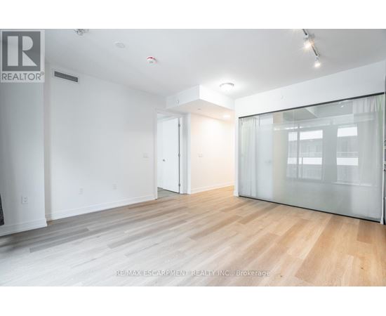 A spacious room with wooden flooring and white walls.
