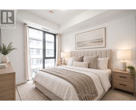 A bedroom with a large bed, a window with curtains, and a framed picture on the wall.