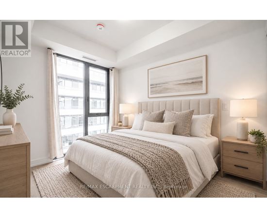 A bedroom with a large bed, a window with curtains, and a framed picture on the wall.