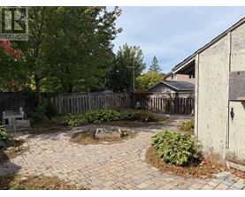A backyard with a brick patio and a wooden fence.