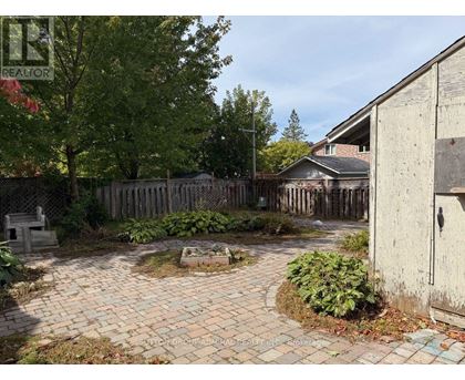 A backyard with a brick patio and a wooden fence.