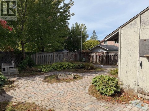 A backyard with a brick patio and a wooden fence.