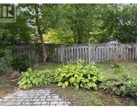 A backyard with a fence and a brick pathway.