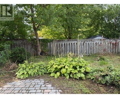A backyard with a fence and a brick pathway.