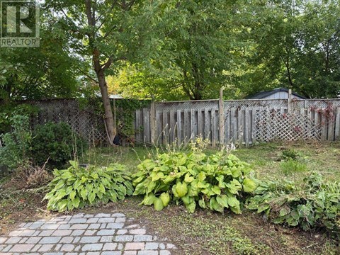 A backyard with a fence and a brick pathway.