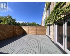 A wooden deck with a fence and a building with glass doors in the background.