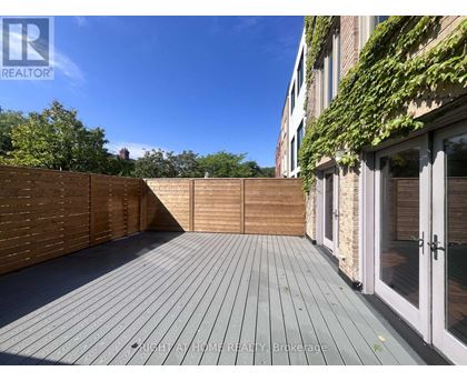 A wooden deck with a fence and a building with glass doors in the background.