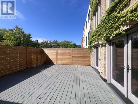 A wooden deck with a fence and a building with glass doors in the background.