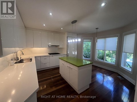 A kitchen with white cabinets and a green island.