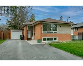 A house with a brown brick exterior and a white garage door is for sale.