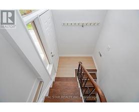 A staircase with a wooden handrail and a white wall.
