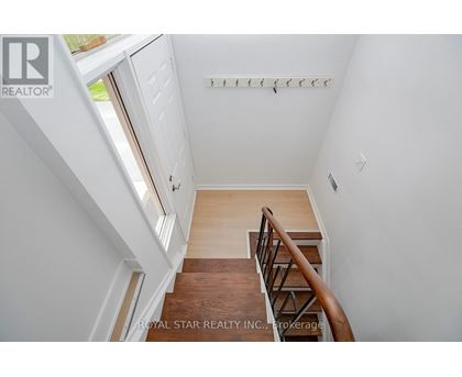A staircase with a wooden handrail and a white wall.