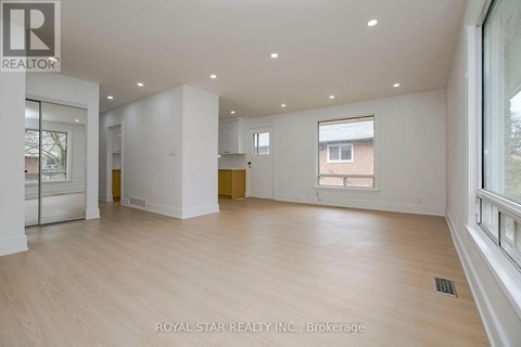 A spacious room with wooden flooring and white walls, part of a property brokerage by Royal Star Realty Inc.