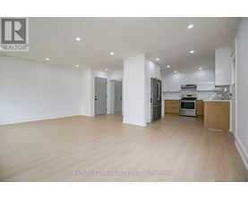 A spacious kitchen with white cabinets and a wooden floor.