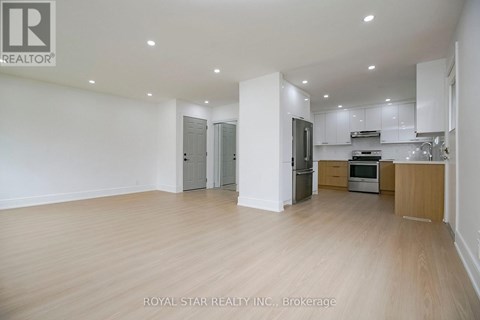 A spacious kitchen with white cabinets and a wooden floor.
