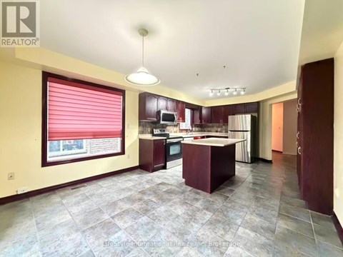 A spacious kitchen with a large island and a window with red blinds.
