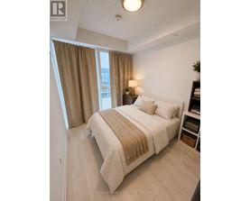A bedroom with a bed, nightstand, and window with curtains.