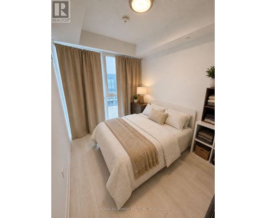 A bedroom with a bed, nightstand, and window with curtains.