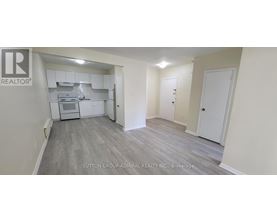 A realtor logo is on the wall of a room with a kitchen area.