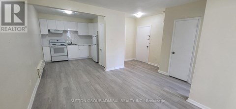 A realtor logo is on the wall of a room with a kitchen area.