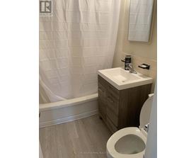 A white sink in a bathroom with a toilet and a shower curtain.
