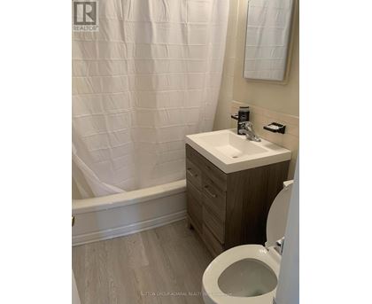 A white sink in a bathroom with a toilet and a shower curtain.