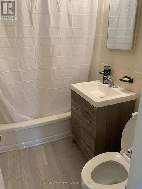 A white sink in a bathroom with a toilet and a shower curtain.