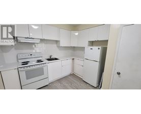 A white kitchen with a stove, sink, and refrigerator.