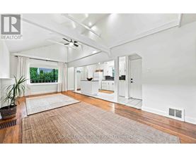 A well-lit, spacious room with a rug on the floor and a ceiling fan.
