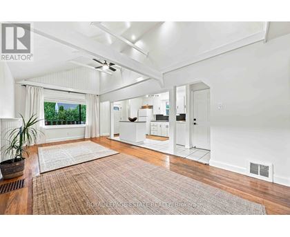 A well-lit, spacious room with a rug on the floor and a ceiling fan.