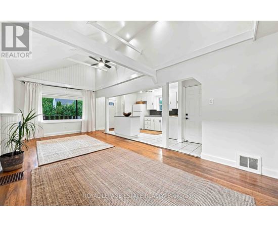 A well-lit, spacious room with a rug on the floor and a ceiling fan.