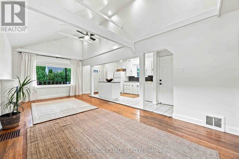 A well-lit, spacious room with a rug on the floor and a ceiling fan.