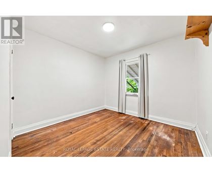 A room with wooden floors and white walls, with a door open to a balcony.