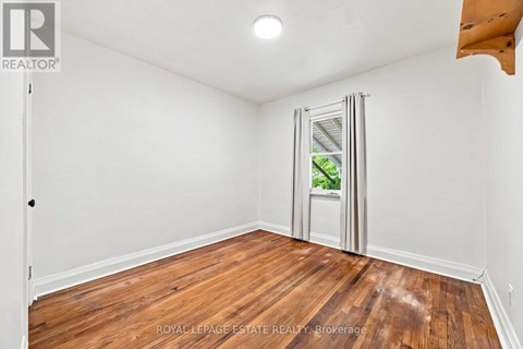 A room with wooden floors and white walls, with a door open to a balcony.