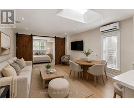 A well-lit, spacious living room with a television, a sofa, a coffee table, and a dining table.