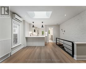 A spacious room with a skylight and a balcony with a railing.