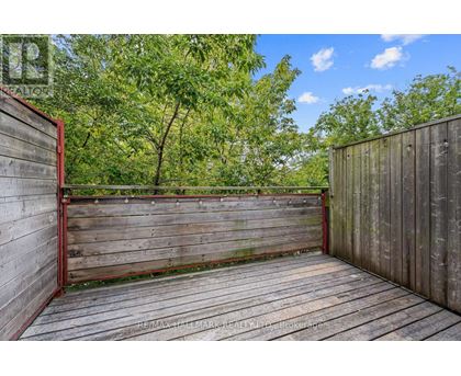 A wooden deck with a red railing and trees in the background.