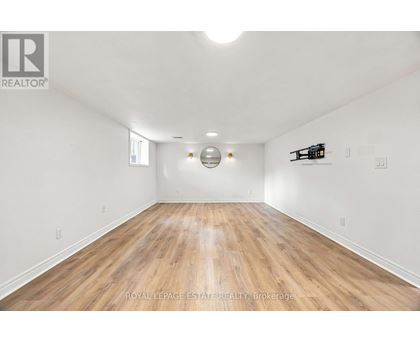 A spacious room with wooden flooring and white walls.