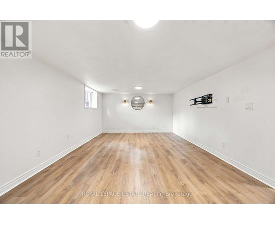 A spacious room with wooden flooring and white walls.