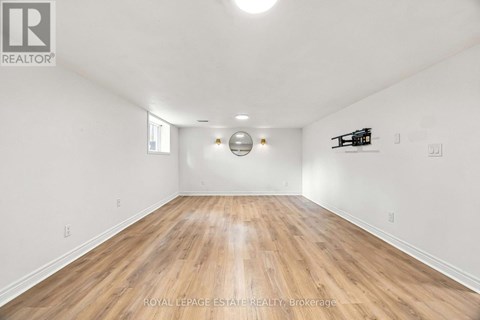 A spacious room with wooden flooring and white walls.